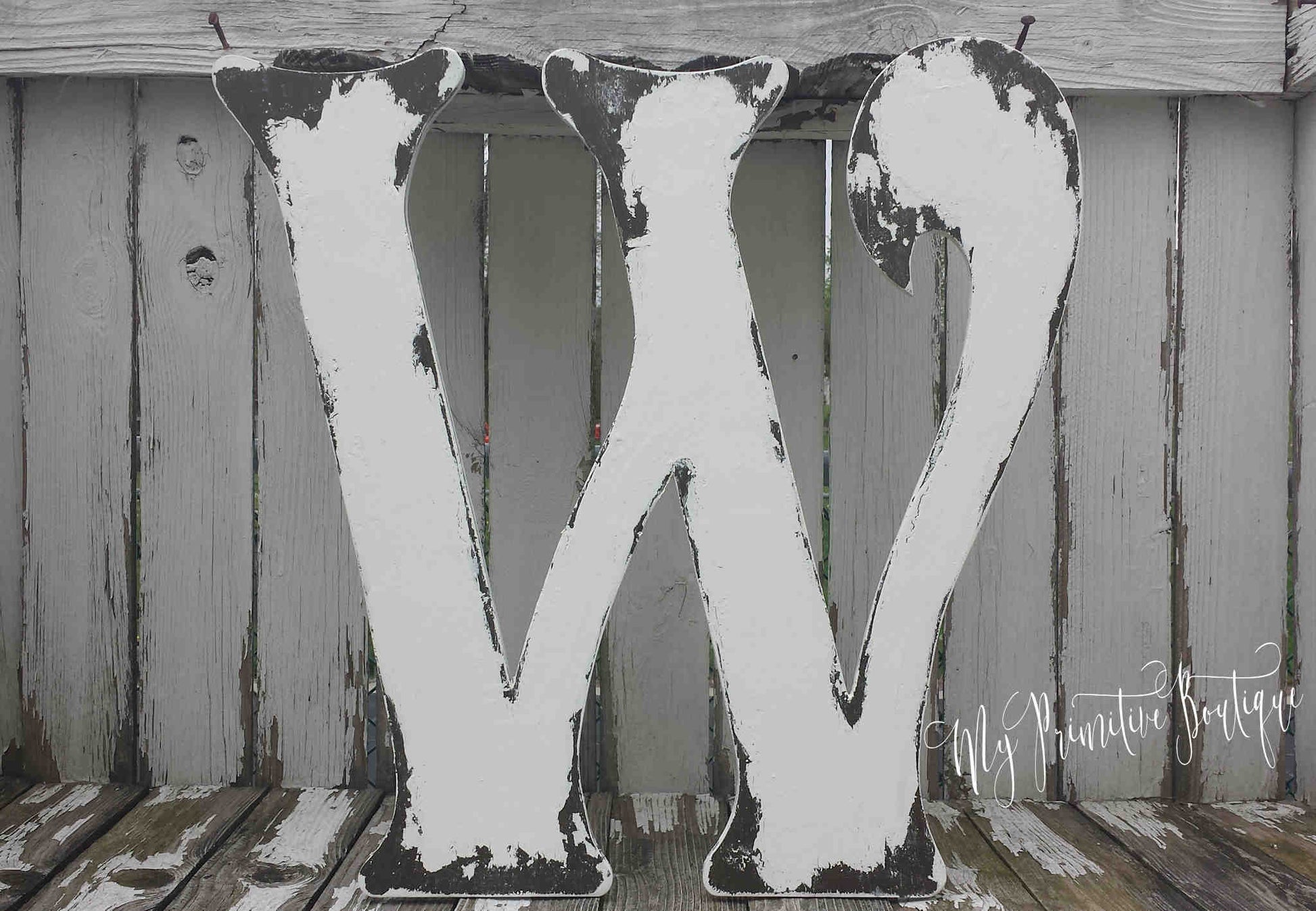 Large wooden letter 'W' with a rustic finish on a wooden surface.