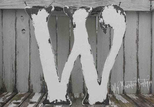 Large wooden letter 'W' with a rustic finish on a wooden surface.