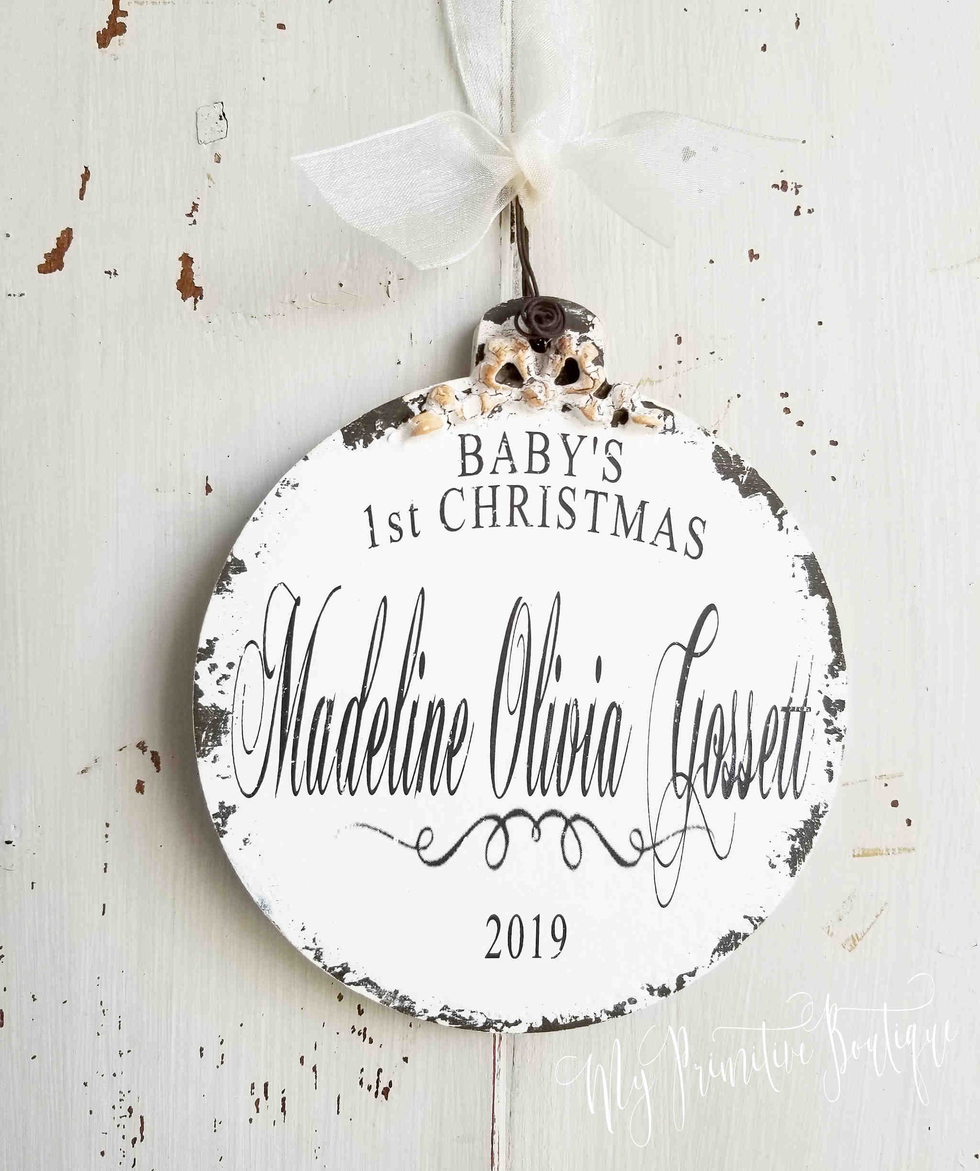 Wooden ball ornament personalized with 'Baby's 1st Christmas' with name and year with a rustic hand-painted finish.