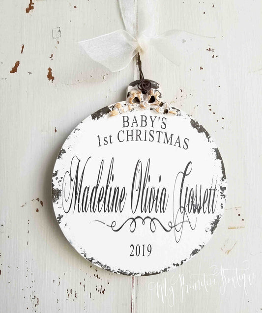 Wooden ball ornament personalized with 'Baby's 1st Christmas' with name and year with a rustic hand-painted finish.