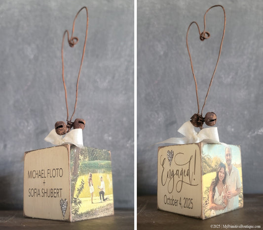 Four-sided personalized engagement ornament showing front and back designs with names, date, and engagement photos. Handmade rustic decor with wire heart hanger and vintage distressed finish.